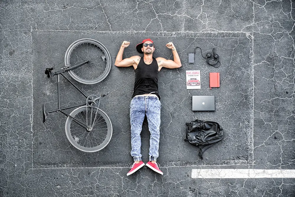 homme couché sur le sol avec son vélo et ses appareils techno